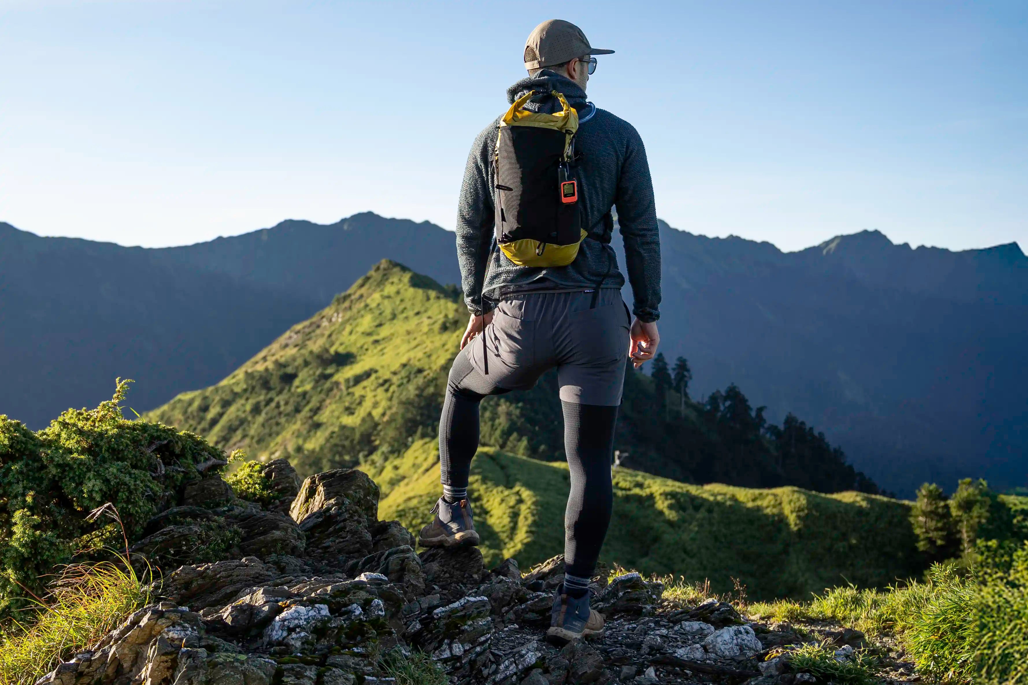 Hiker standing on a mountain top with an ultralight backpack taking in the views